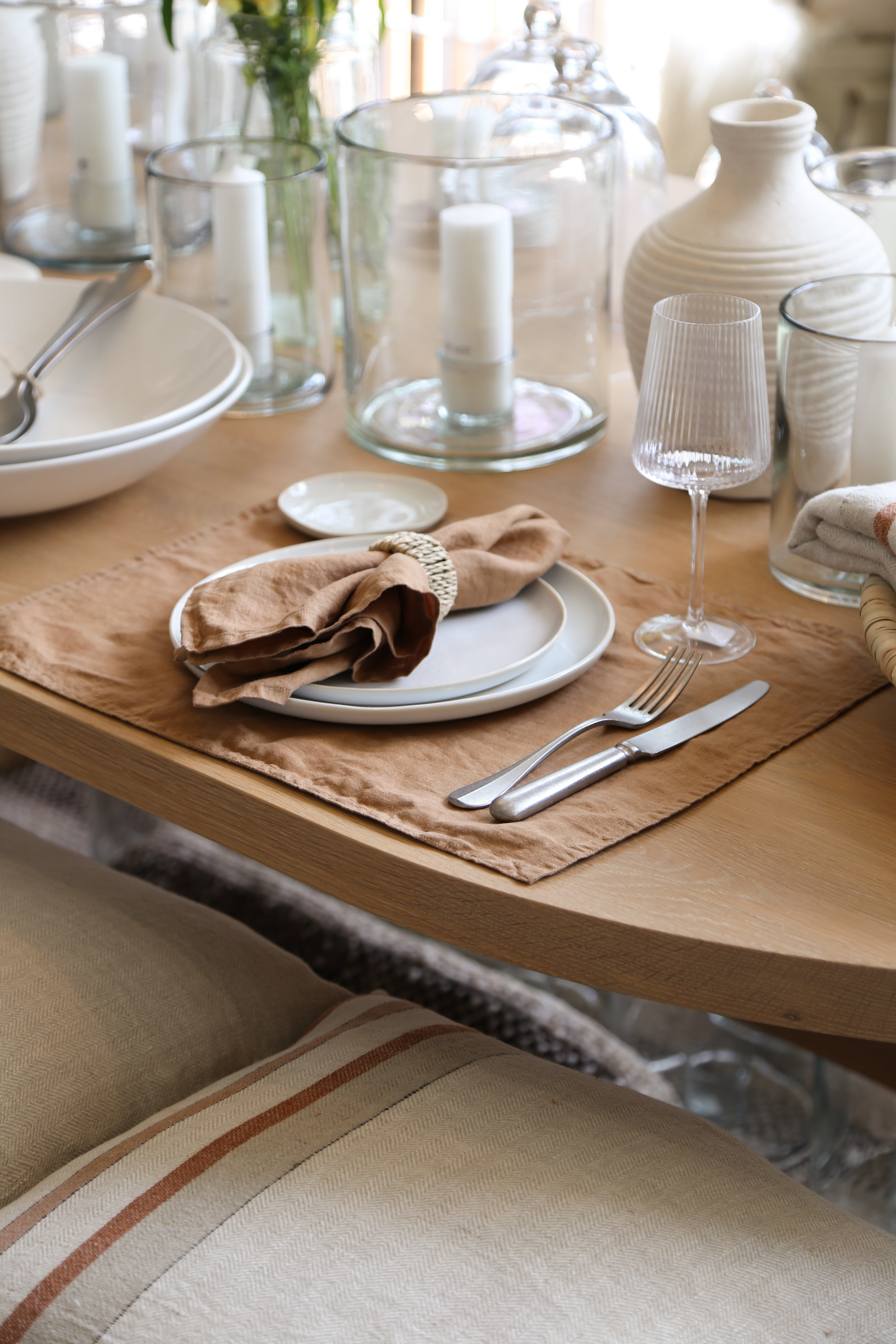 Dining table setting with plates, napkins, and glasses on a wooden table.