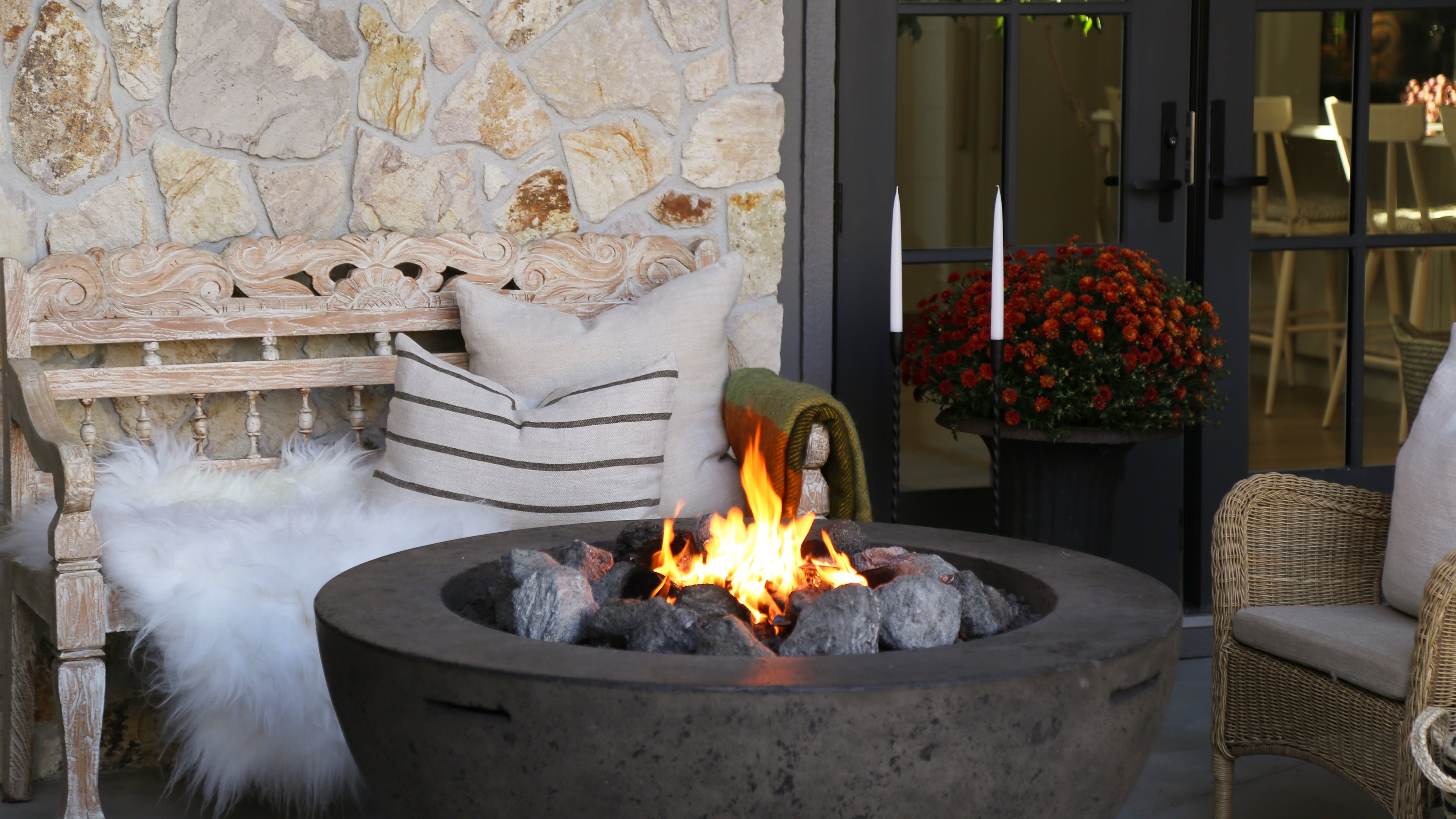 Outdoor setting with a fire pit, stone wall, and patio furniture.
