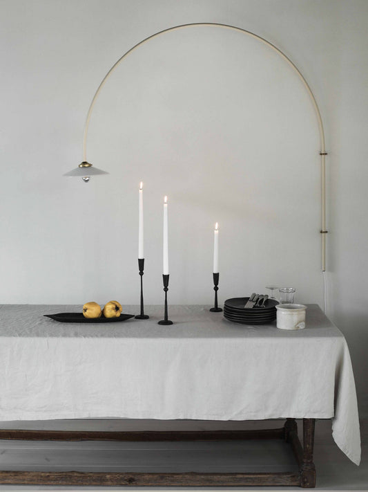 Dining table with white tablecloth, candles, and fruit under an archway.