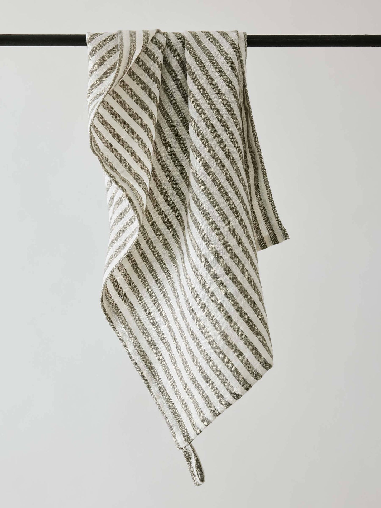 Striped tea towel hanging on a rod against a plain background