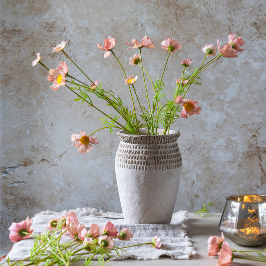 White textured vase with pink flowers on a textured surface