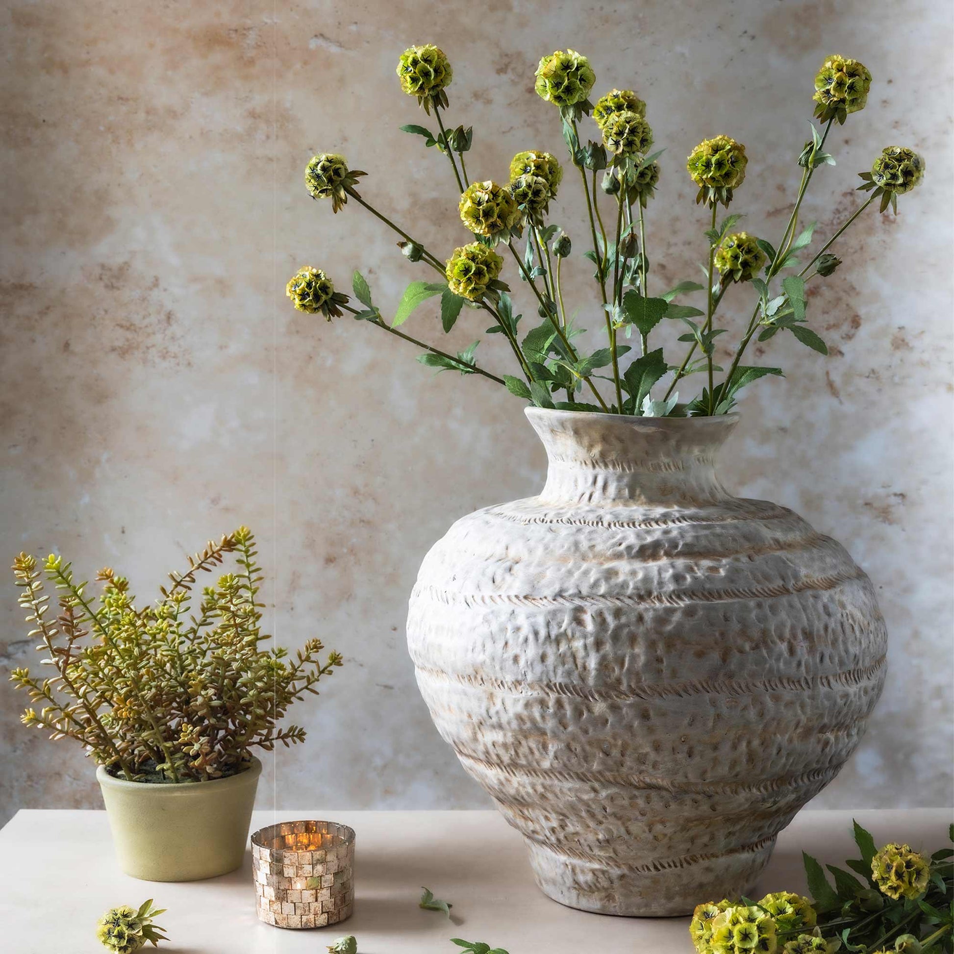 Decorative vase with green flowers on a textured wall background