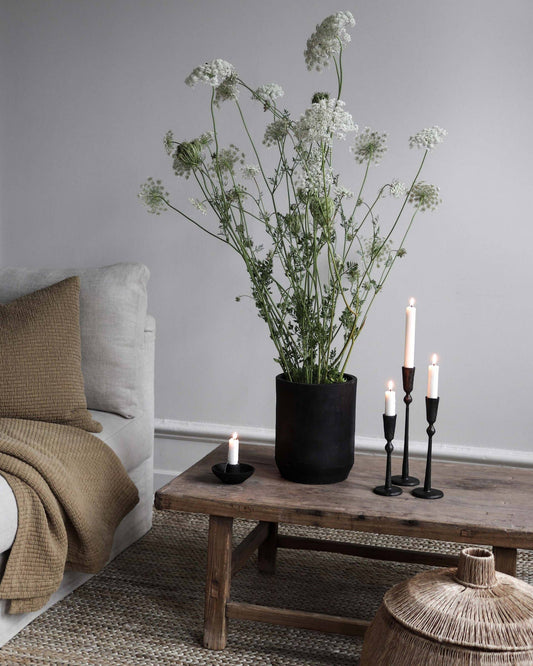 Living room with a wooden coffee table, black vase with greenery, and candles.