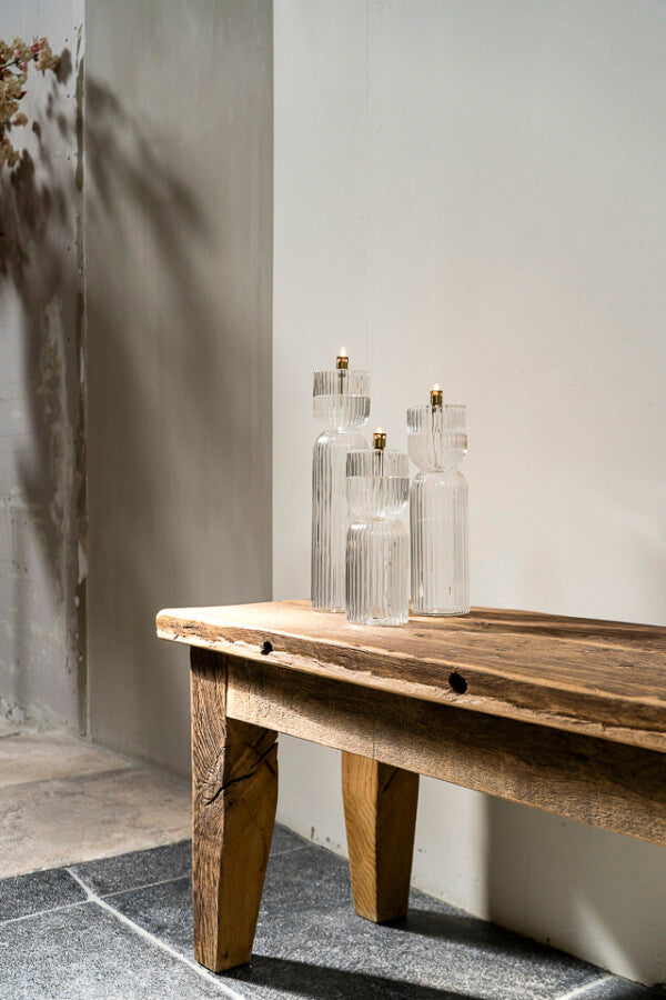 Wooden bench with set of three oil lamps on a neutral background