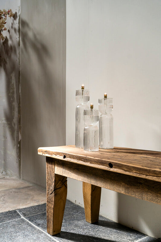 Wooden bench with set of three oil lamps on a neutral background