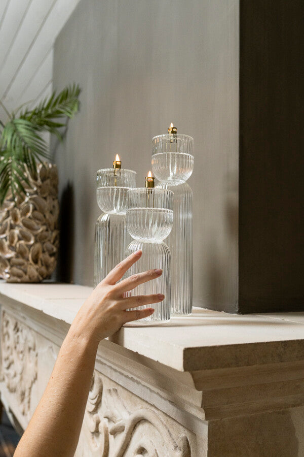 Set of three oil lamps on a shelf with a hand reaching out